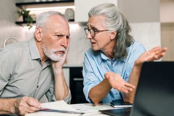 A couple discusses family finances while using a laptop at home