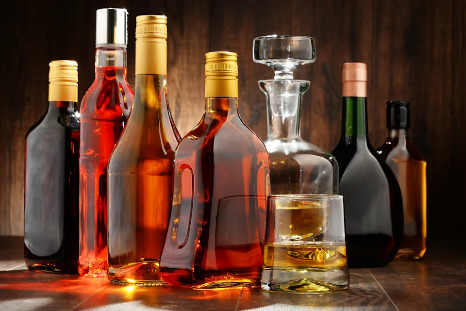 Various bottles of alcohol and a glass filled with air are arranged on a wooden table