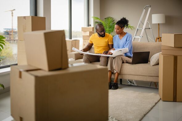 A couple is planning to move into a new house surrounded by boxes and a laptop on the sofa A couple is planning to move into a new house surrounded by boxes and a laptop on the sofa