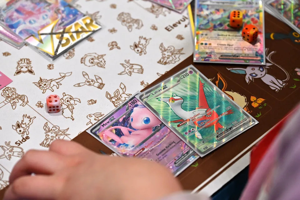 A trading card game player with Pokémon cards and dice on a themed mat